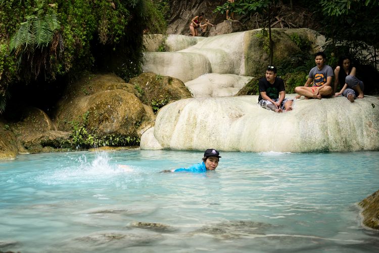 Woman swimming in seventh tier at Erawan Falls in Kanchanaburi Thailand