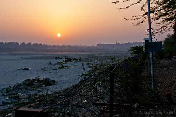 Sunset over barbed wire fence along Yamuna River