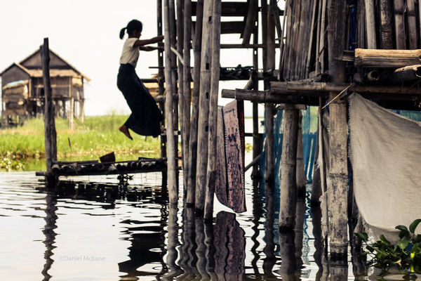 Burmese woman climbing into stilt house on Inle Lake