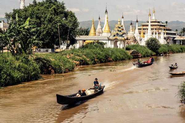 Boat passing temple and stupas on Inle Lake