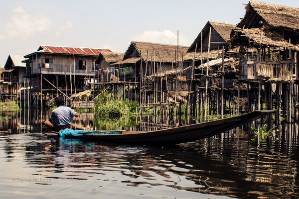 man in boat in stilt house village Myanmar