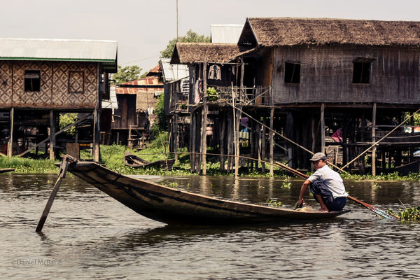 Man rowing boat in village in Myanmar