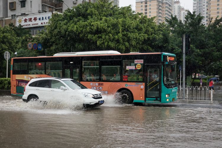 Car passes bus on flooded road in China