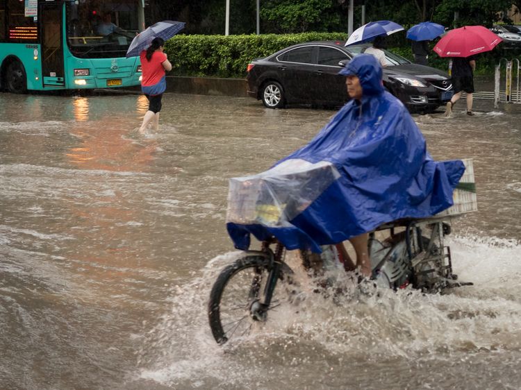Man with poncho on motorcycle in Shenzhen flood
