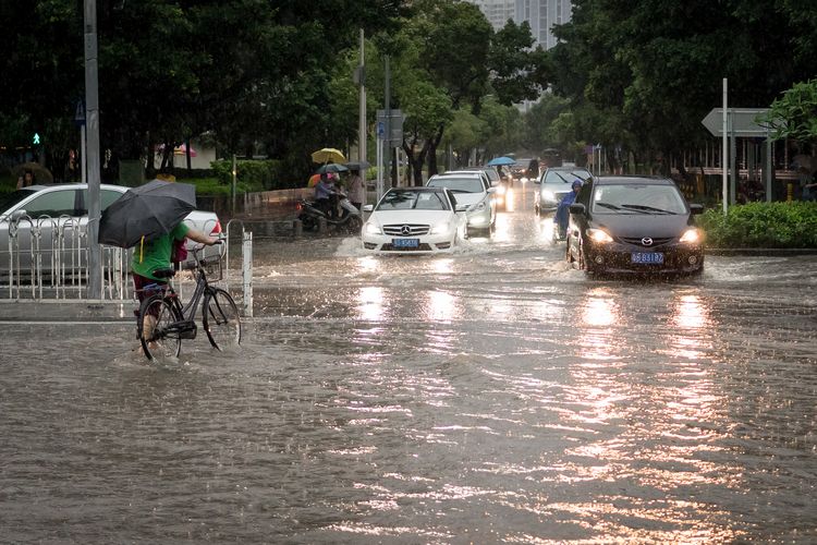 Pushing a bike through the flooded streets in China
